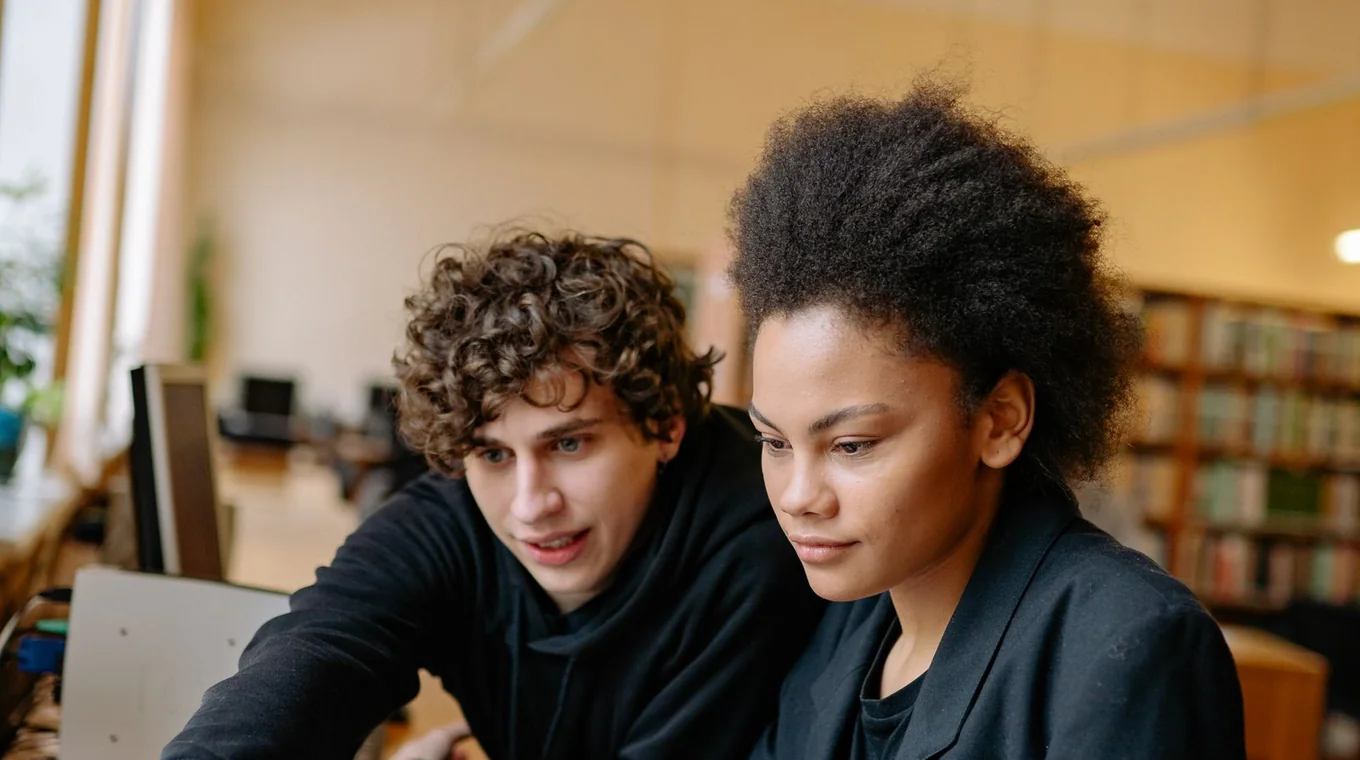 Fotografia ilustrativa de dois estudantes jovens, homem e mulher, estudando para concurso.